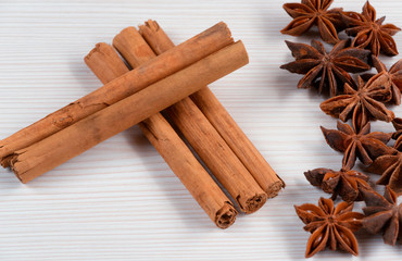 Cinnamon sticks and star anise on white wooden background.