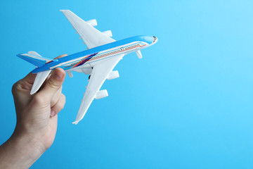 Toy airplane in hand on a blue background
