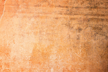 Weathered, aged and scratched orange concrete wall texture background with vignetting.