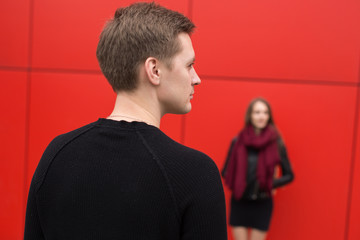 Young man and woman in passion, emotion, on the street with a backdrop of the red wall. Fashion