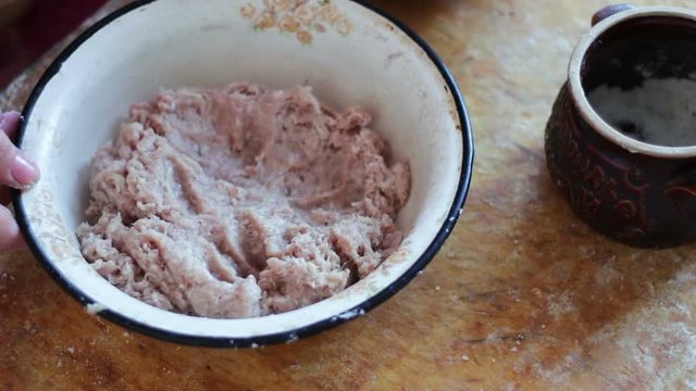 Hands are stirring minced meat in a bowl