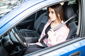 Portrait of young woman fasten seat belt in her car