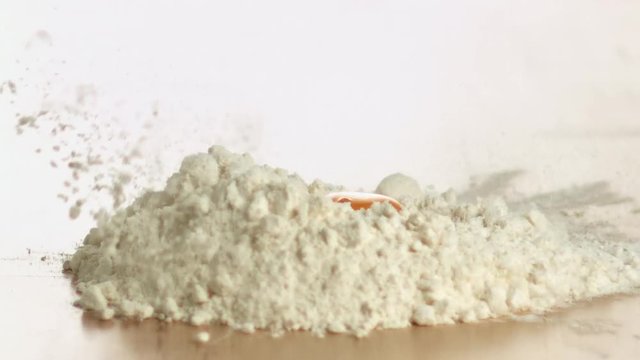 jaune d&rsquo;&oelig;uf tombant sur une fontaine de farine en slow motion