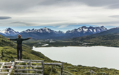 Fototapeta na wymiar man standing on the stone above lake in patagonia with grey sky