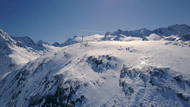 Father and daugther are standing on the hill and having a photosession. Scenic winter aerial flight of drone over the mountains and ski resort. Beautiful panorama, sunny day. Obergurgl, Austria. 4K.