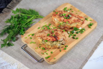 The baked chicken fillet with a stuffing in sauce with seasonings on a gray background