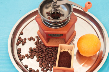 Manual coffee grinder with coffee grains on a tray