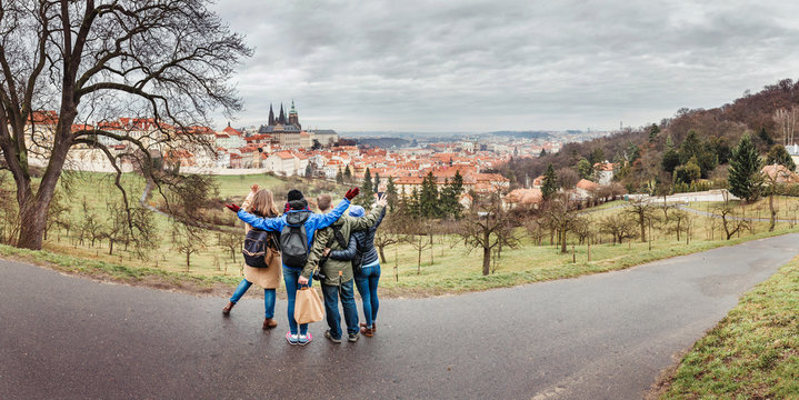 Back View Of Group Of People Hugging In Prague Park At Spring. Travel With Friends Concept