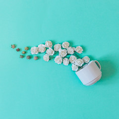 white flowers pour out from a Cup on a green background. the concept of hot drink: coffee or tea for Breakfast. minimal flat lay.