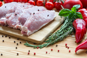 Raw pork on cutting board and vegetables