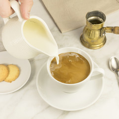 Fototapeta na wymiar Milk poured into cup of coffee