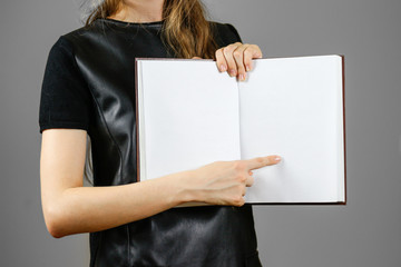 Closeup of girl in black dress holding blank open white book on isolated background. Education...