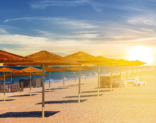 sea beach with sun umbrella at the sunset