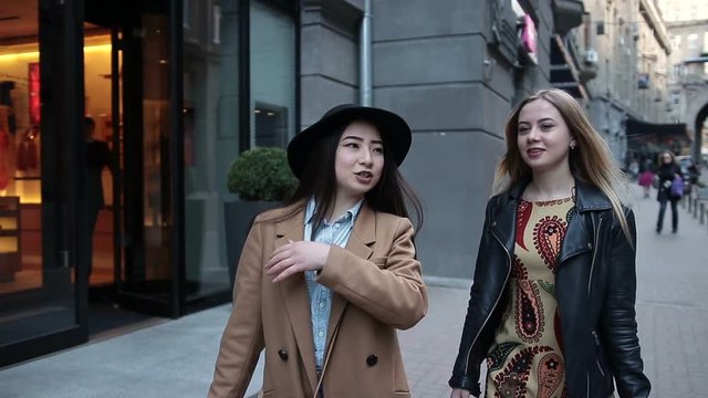 Two young women with shopping bags walking in city