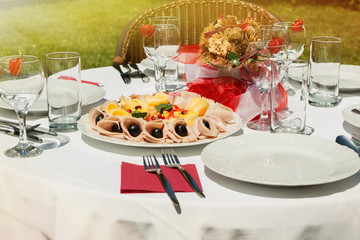 Sunlit cold plate with cheese and ham and fruit. Decorated table in the garden