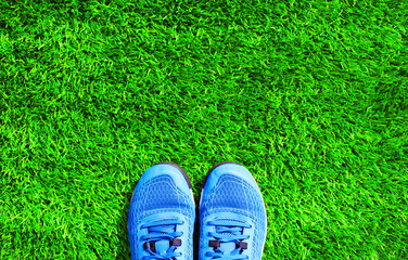 Part blue sports sneakers on the green grass textured background, top view