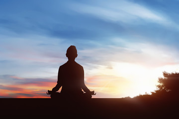 Silhouette of young woman practicing yoga in outdoor