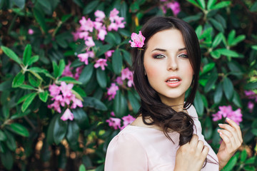 Naklejka premium Outdoor fashion photo of beautiful young woman surrounded by flowers. Spring blossom