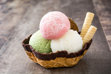 Ice cream scoops served in waffle basket on wooden background

