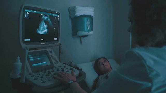 Ultrasound machine doctor s hand usg investigation USCG. Closeup of woman getting an ultrasound scan on abdominal by doctor. Screen of echo-cardiography (ultrasound) machine.