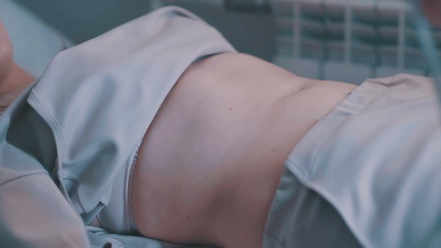 Young woman on ultrasound of abdominal cavity. Ultrasound machine doctor's hand usg investigation. Medical Equipment ultrasound scanning. Echo machine, ultrasound machine.