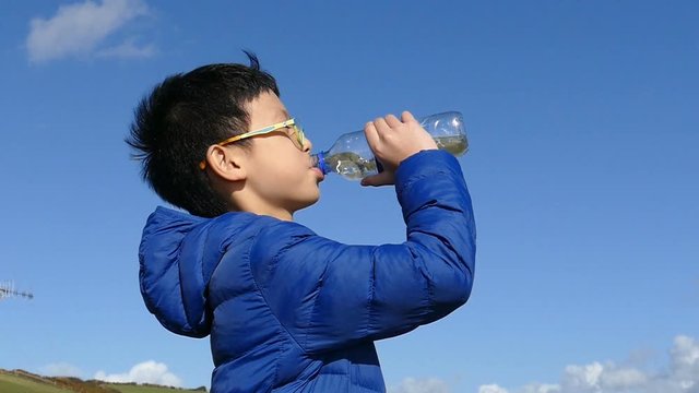 Young asian boy drinks water from a bottle,slow motion
