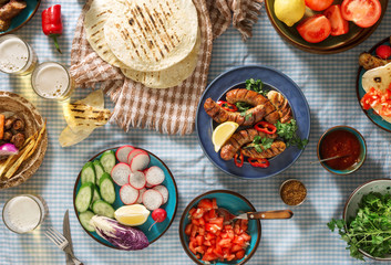 Dinner party table with grilled sausage, beer and different dishes
