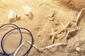 Fototapeta na wymiar Badminton rackets, net, shuttlecock and starfish on the sand