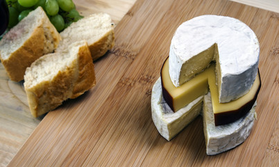 Cheeses stacked on cheese board - brie, smoked cheese & camembert.
