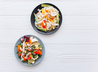 salad and pasta with seafood on wooden background 