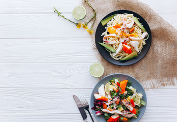 salad and pasta with seafood on wooden background 
