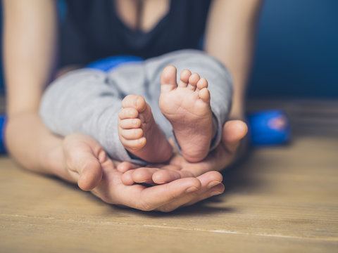 Woman cupping feet of baby