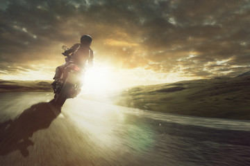 Motorrad fährt  durch eine Kurve bei Sonnenuntergang
