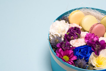 Box with flowers and macaroons on blue background