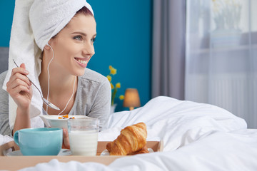 Portrait of a happy smiling latino hispanic woman eating a healthy breakfast in bed.