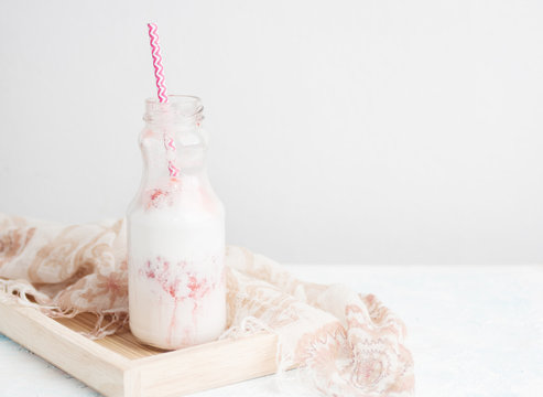 Strawberry milkshake in glass bottle with summer scarf on white table