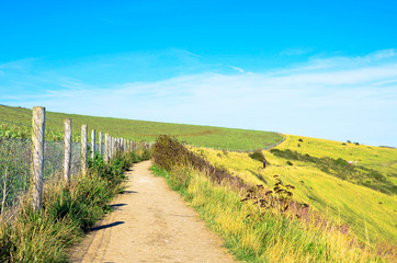Fototapeta na wymiar Walking on a countryside footpath by a wooden fence 