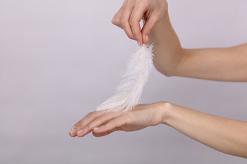 Woman touching her smooth perfect hand skin after beauty treatment with feather.