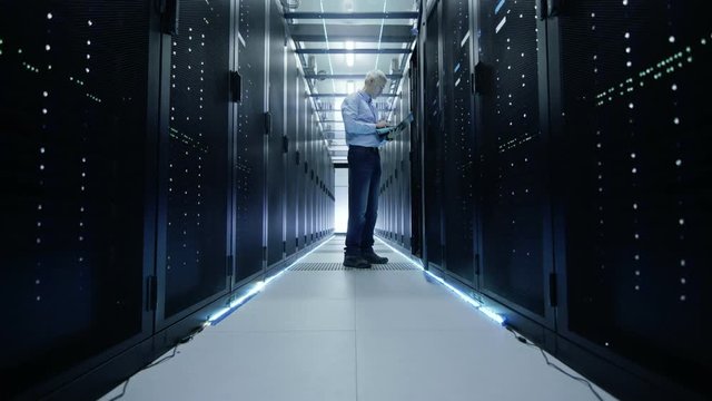 Data Center Door Opens and We See Server Engineer Working on a Laptop. Rack Server Cabinet is Open.  Shot on RED EPIC-W 8K Helium Cinema Camera.