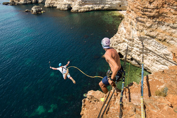 Rope jumping off a cliff with a rope in the water. The ocean. Sea. Mountain.