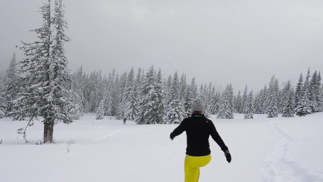Joyful meeting of two travelers in an alpine meadow covered with snow amidst huge fir trees after a snow storm. Amazing winter adventure. Slow motion