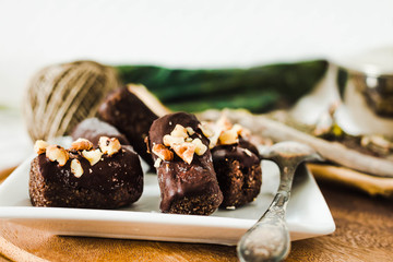 healthy raw chocolate candies with walnuts on a white square plate