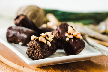 healthy raw chocolate candies with walnuts on a white square plate