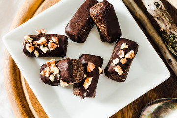 healthy raw chocolate candies with walnuts on a white square plate