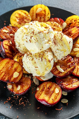 Honey glazed grilled plums with ice cream on black plate