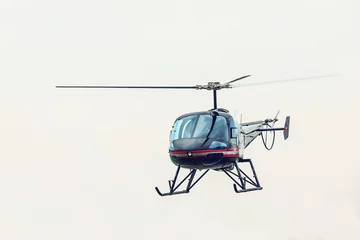 Tuinposter Zwarte helikopter die vooraan vliegt. Lichte multifunctionele helikopter met vijf zitplaatsen, volledig metalen constructie. © murmakova