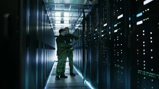 In Data Center Two Military Men Work with Open Server Rack Cabinet. One Holds Military Edition Laptop.  Shot on RED EPIC-W 8K Helium Cinema Camera.