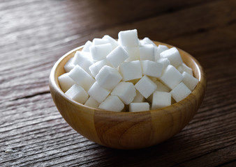 Sugar cubes in wood bowl on wood table