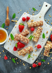 Granola bar with strawberries, raspberry honey and white chocolate on cutting board