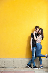 Fototapeta na wymiar Happy couple posing in fashion style on yellow wall. Lifestyle and relationship